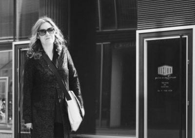 Blinde Frau mit Sonnenbrille vor modernem Gebäude in Berlin, panoramaaufnahme, eleganter Look, urbanes Lifestyle-Bild, professionelle Fotografie, Streetstyle, Mode, städtisches Umfeld, Lifestyle-Fotografie, moderne Architektur.