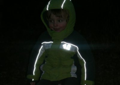 Sonnenlicht reflektierende Kinderjacke bei Dunkelheit, outdoor Kinderspiel, Sichtbarkeit bei Nacht, reflektierende Jacke für Kinder, dunkle Umgebung, Sicherheitskleidung für Kinder.