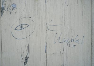 Akte Blick auf eine weiße Holzwand mit einer handgemalten Katze und einem Auge, die einen kreativen und ungewöhnlichen Dekorationsstil zeigen.