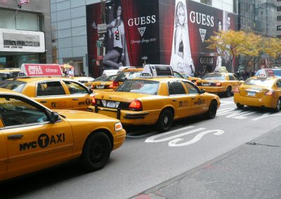 NYC Taxi-Maut mit gelben Taxis in New York City, Straßenverkehrsszene vor großen Modewerbung und Hochhäusern, urbane Umgebung, typisch für Manhattan, Verkehrsknotenpunkt, Reise- und Stadtbild.