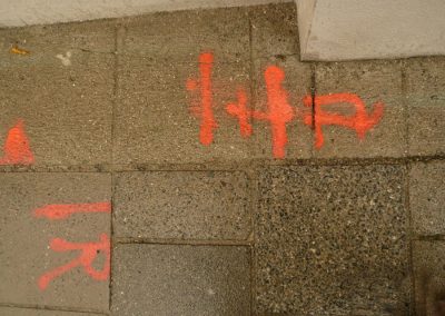 Fluoreszierende Straßenmarkierung auf Gehweg mit Hinweisen für Hunde und Fußgänger in der Stadt, hohe Sichtbarkeit, Sicherheit und Orientierung, Sprayfarbe auf Pflastersteinen, outdoor, urbanes Umfeld, Verkehrssicherheit, Hundetraining, Hundesicherheit.