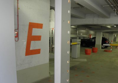 E-Autoparkplatz in Mehrstöckiger Tiefgarage, modern mit Installationen und Parkmarkierungen für effizientes Parken.