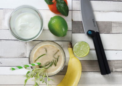 Frischer grüner Limettensaft, Bananen, Joghurt und Zitrusfrüchte mit Küchenmesser auf weißem Holz, ideal für gesunde Smoothie-Rezepte.