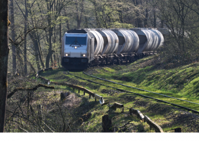 Zug mit modernen Kühlwaggons fährt durch ein ländliches Waldgebiet in Deutschland.