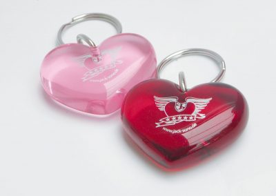 Herzförmige Schlüsselanhänger in Pink und Rot mit Sono Cats Logo, ideal als Schlüsselaccessoire, Autozubehör oder Geschenk, hochwertig und langlebig, mit praktischen Metallringen.